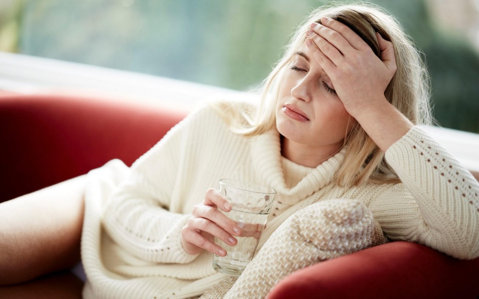 Ženska v belem puloverju in kozarcem v roki se drži za glavio-alkoholni maček