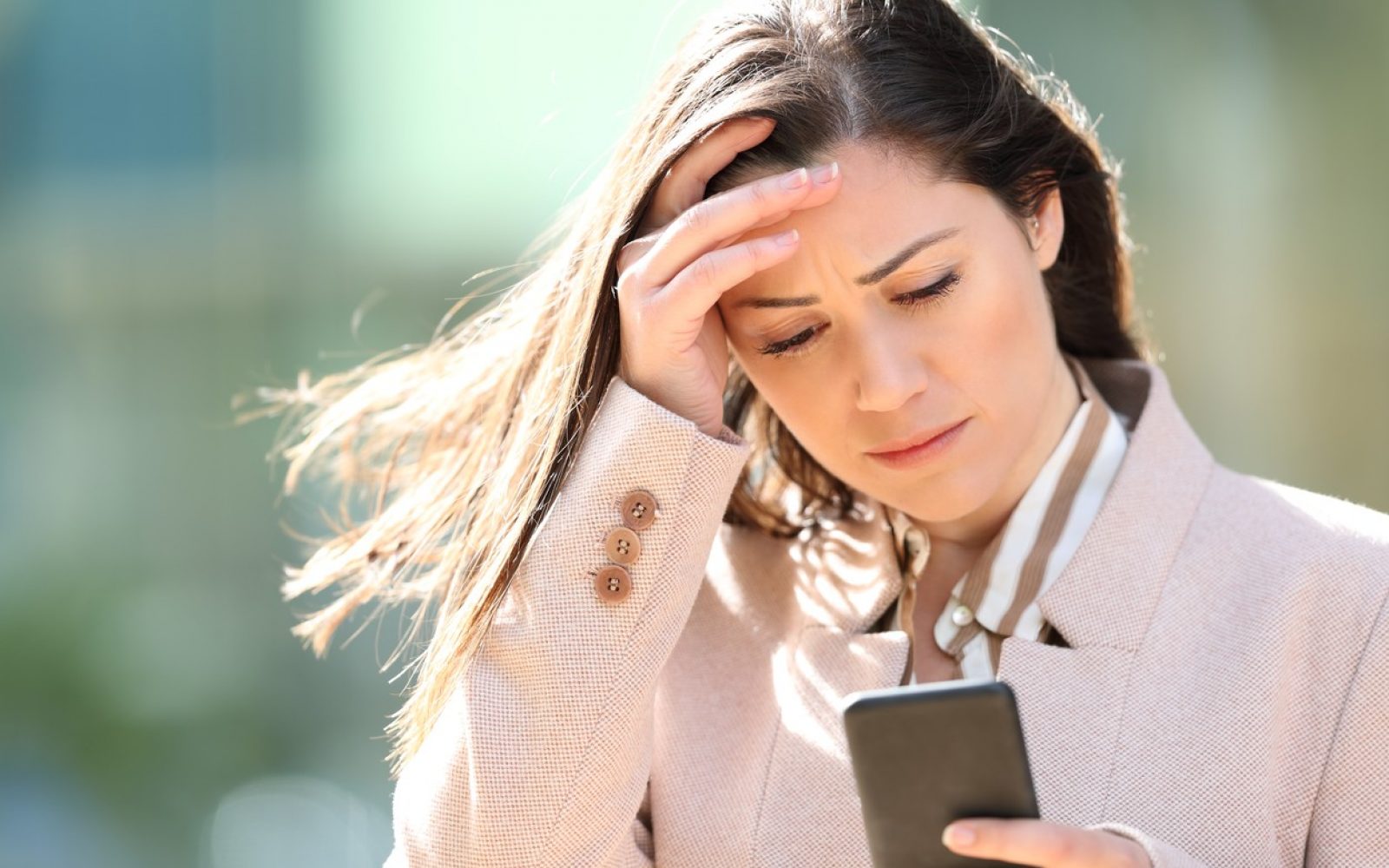 Ženska zaskrbljeno gleda v telefon