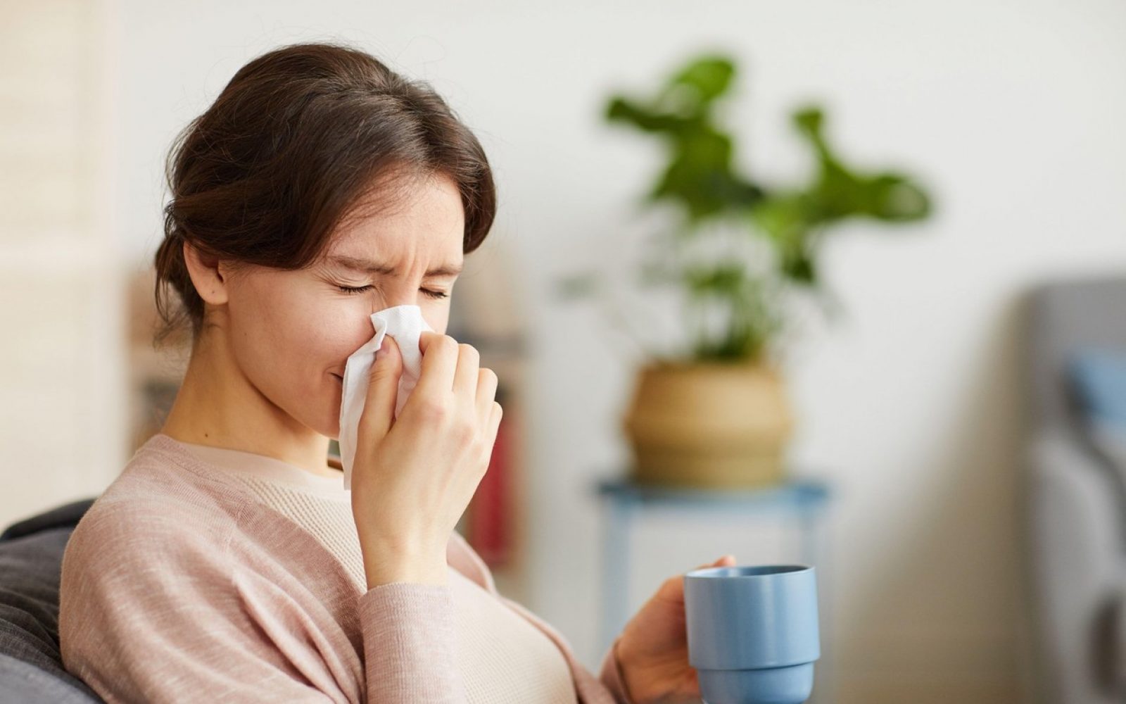 Ženska z rjavimi lasmi si briše zamašen nos.