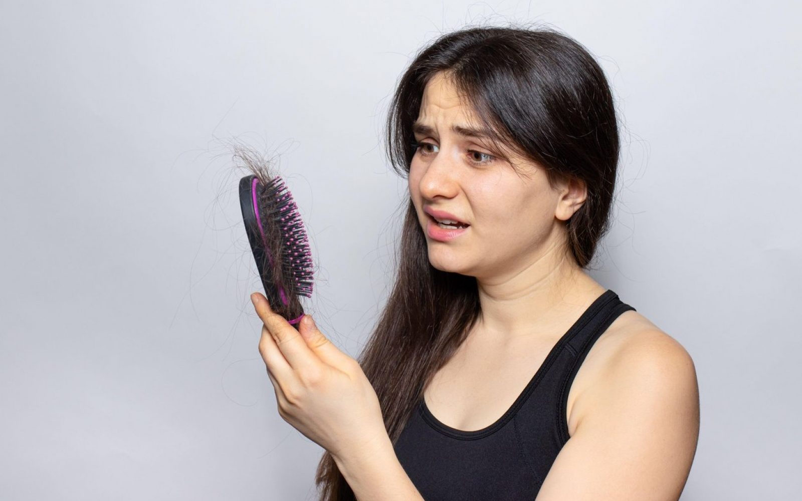 izpadanje las, rjavolaska drži v roki krtačo