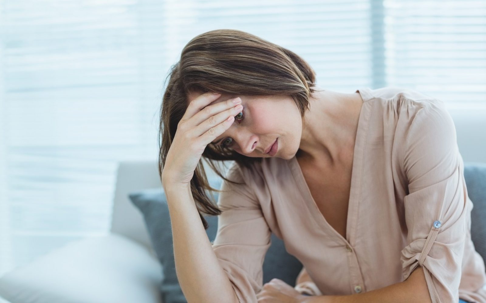 Sklonjena žalostna ženska se drži za glavo