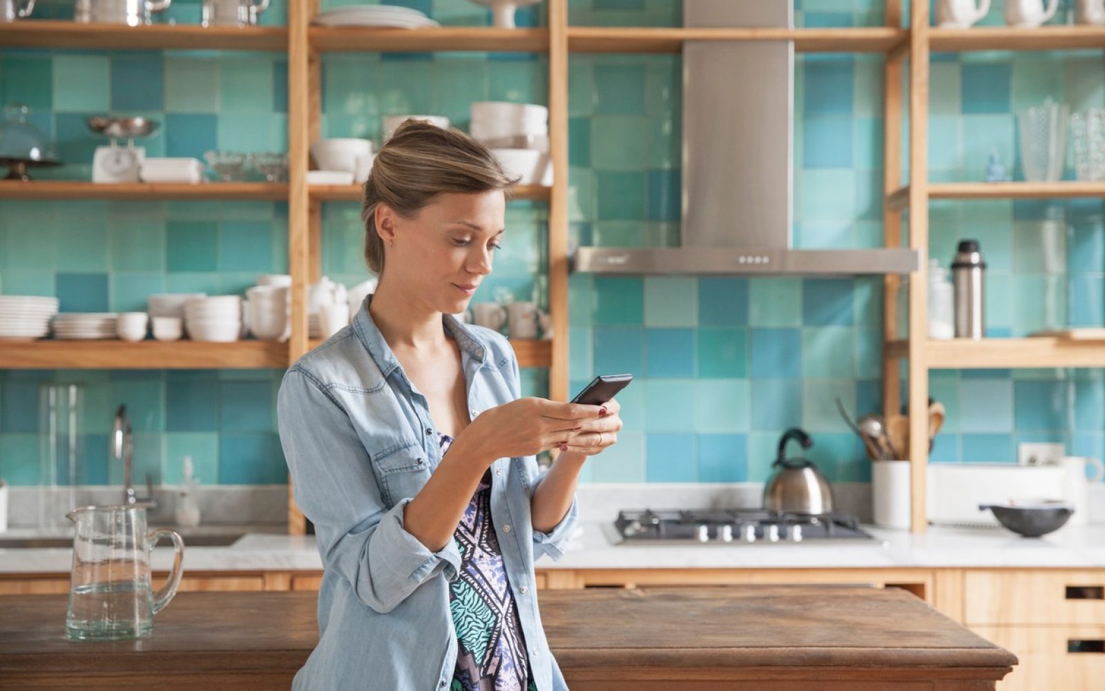 zenska gospodinja s telefonom v kuhinji