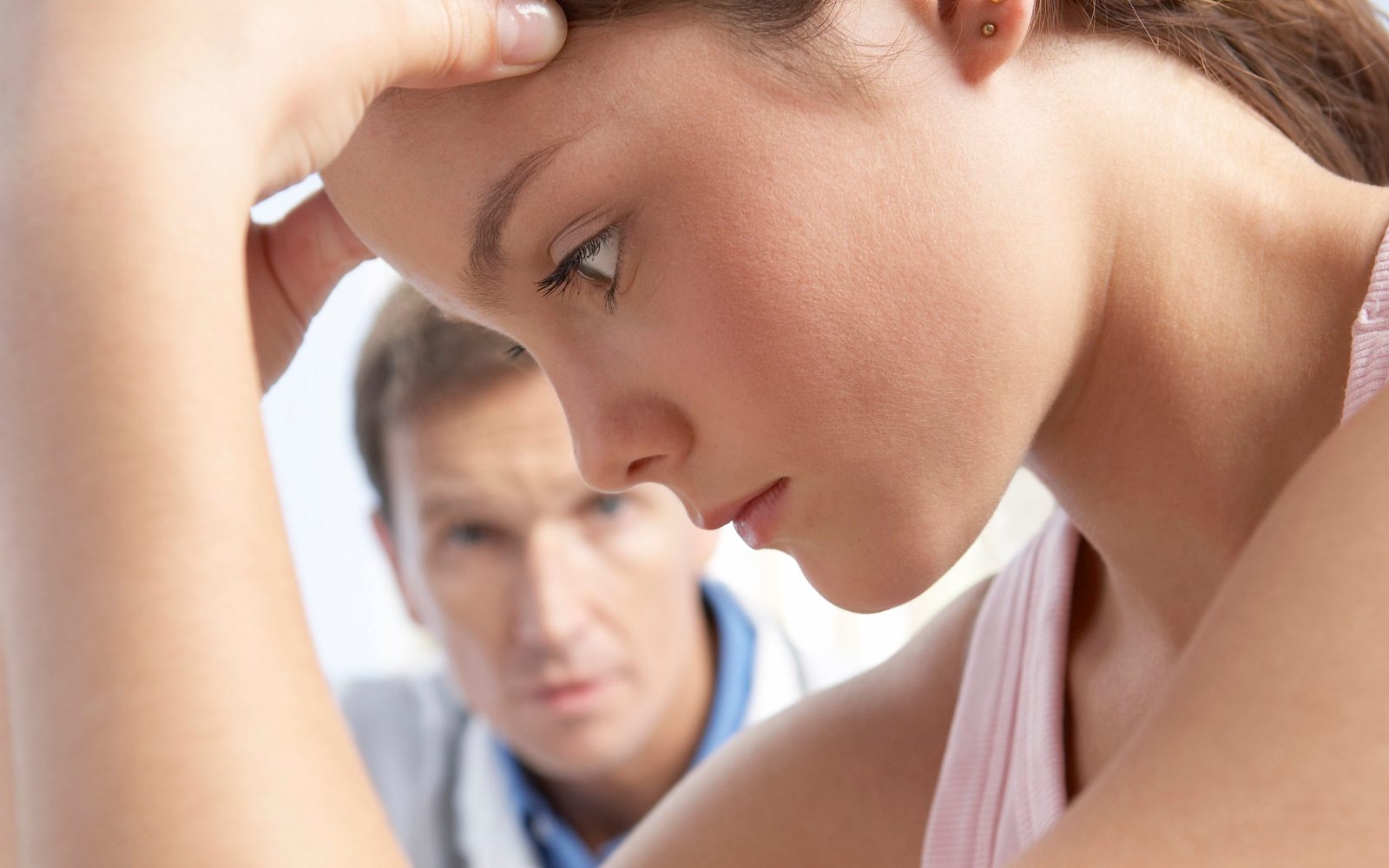 Zaskrbljena ženska odmika pogled pred moških, ki ji želi pomagati.