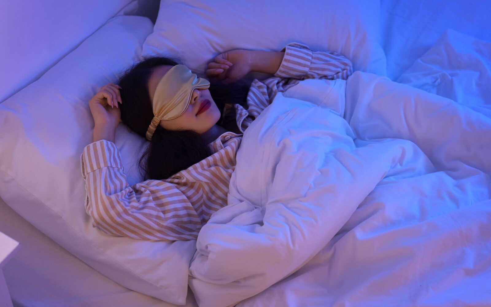 Pomen spanja v temi - ženska v postelji s spalno prevezo za oči