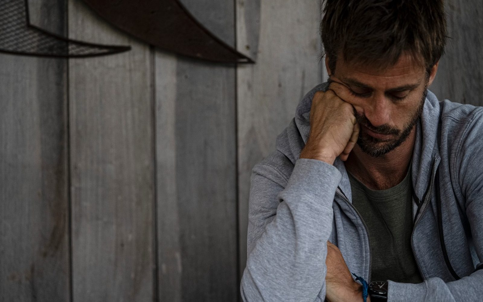 Žalosten moški sedi, glavo si podpira s pestjo