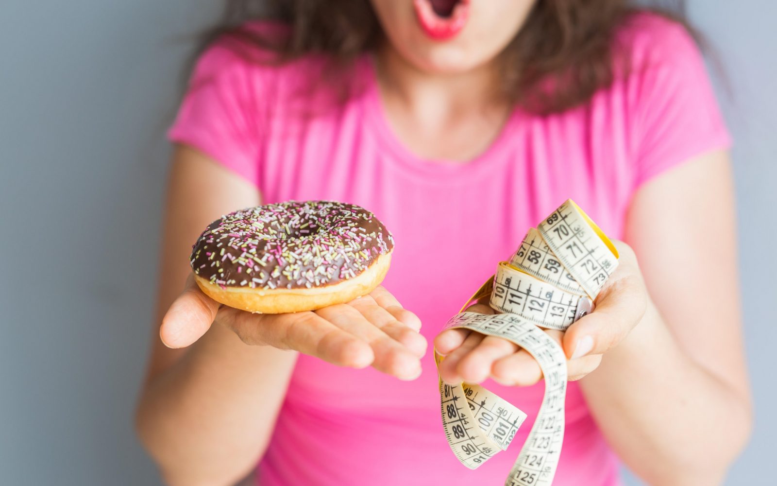 Deklica v rokah drži krof in meter