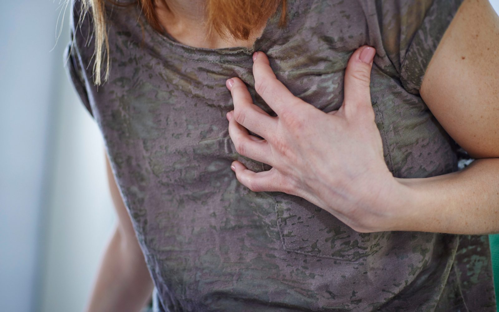 Ženska se drži za predel prs, bolečina pri srčni kapi, pri srčnem infarktu