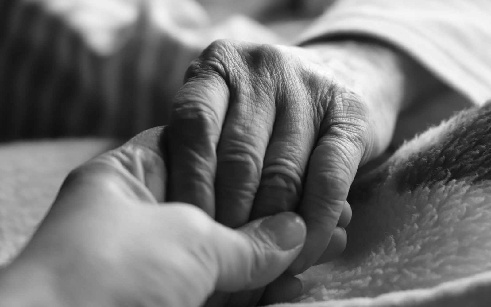 Mlajša ženska drži za roko starejšo osebo