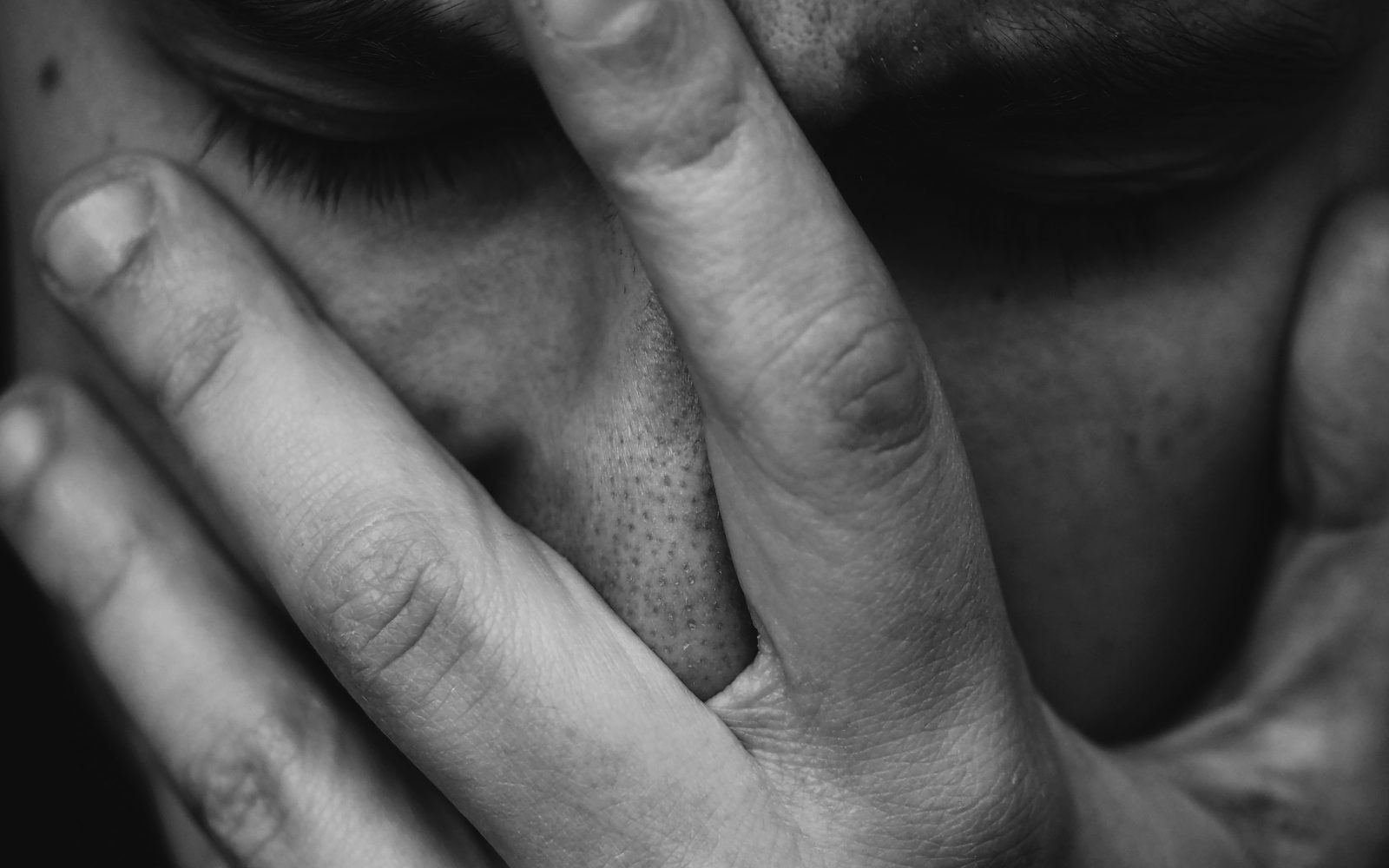 Moški se drži za obraz