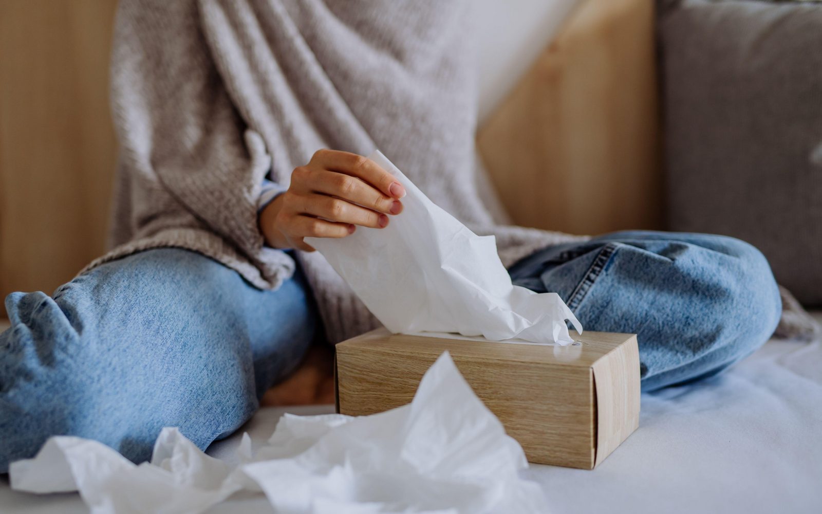 Prehlajena ženska iz škatle za robčke vzema robček