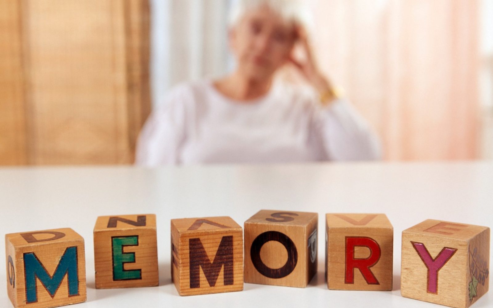 V ozadju se ženska drži za glavo, v ospredju je napis spomin v angleščini (memory)