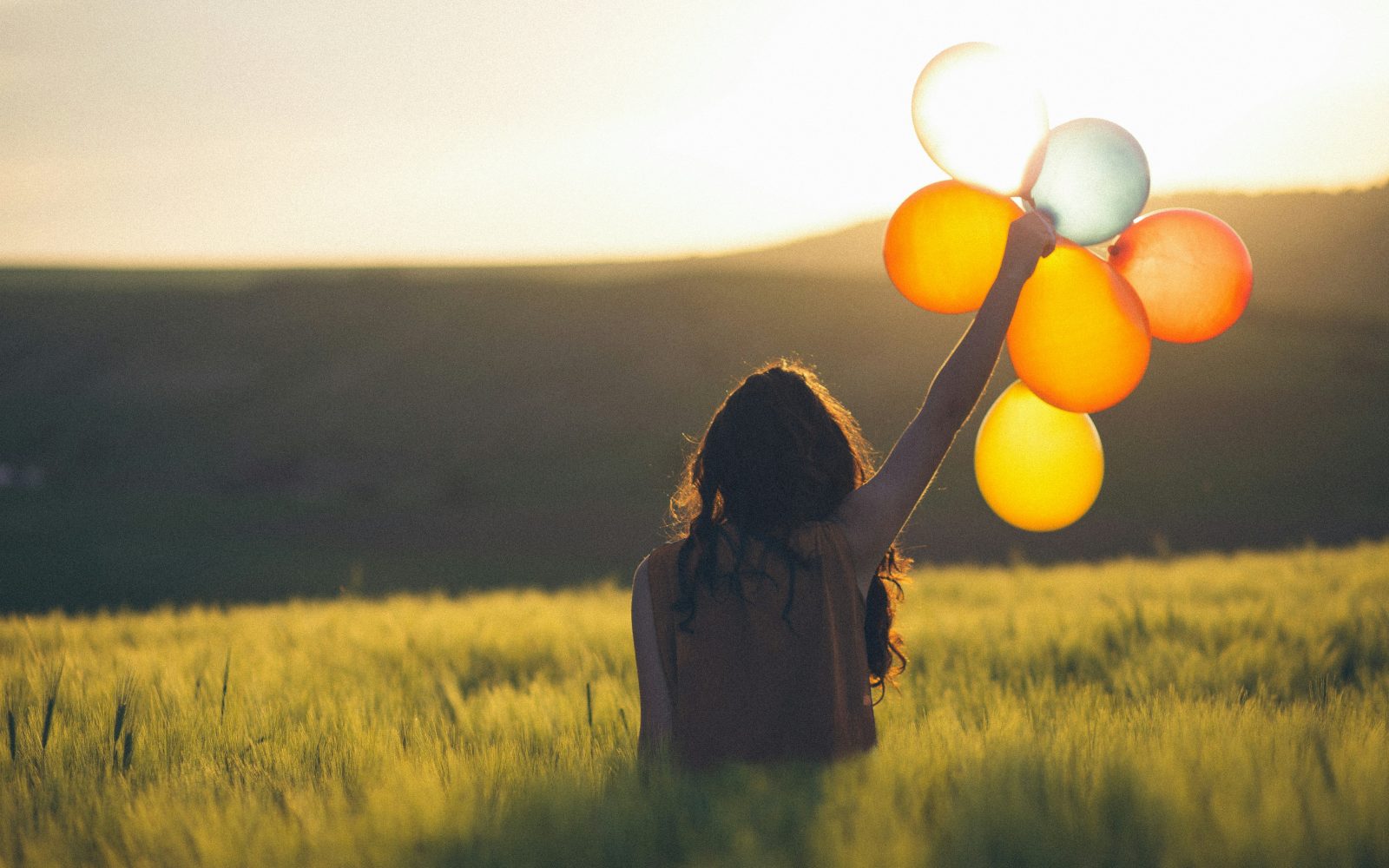 Ženska na travniku drži v rokah balone