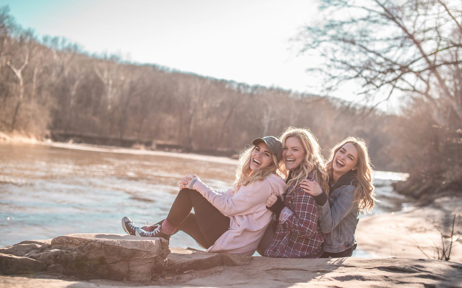 Tri ženske sedijo na nabrežju in se smejijo