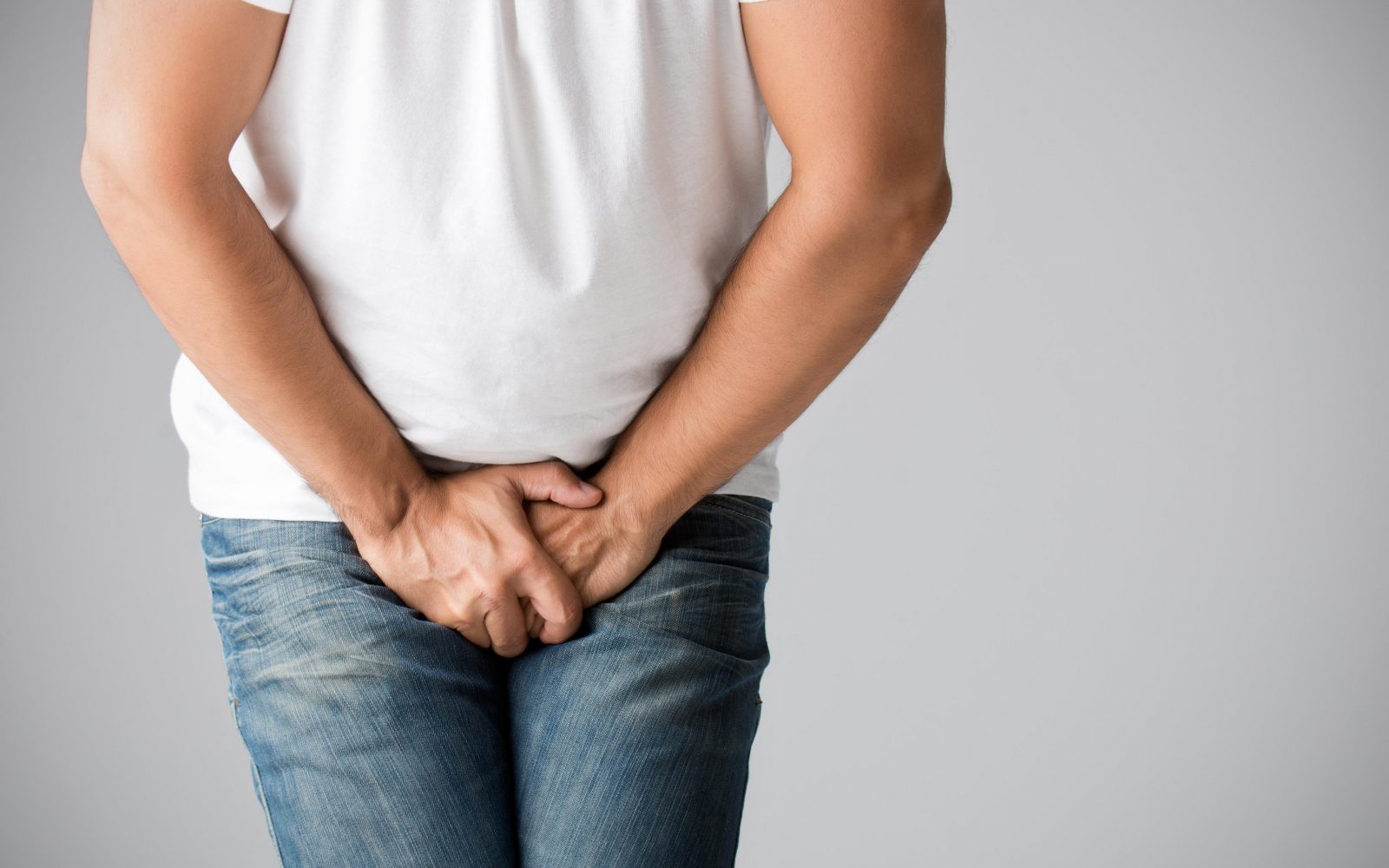 Moški se z rokami boli za mednožje