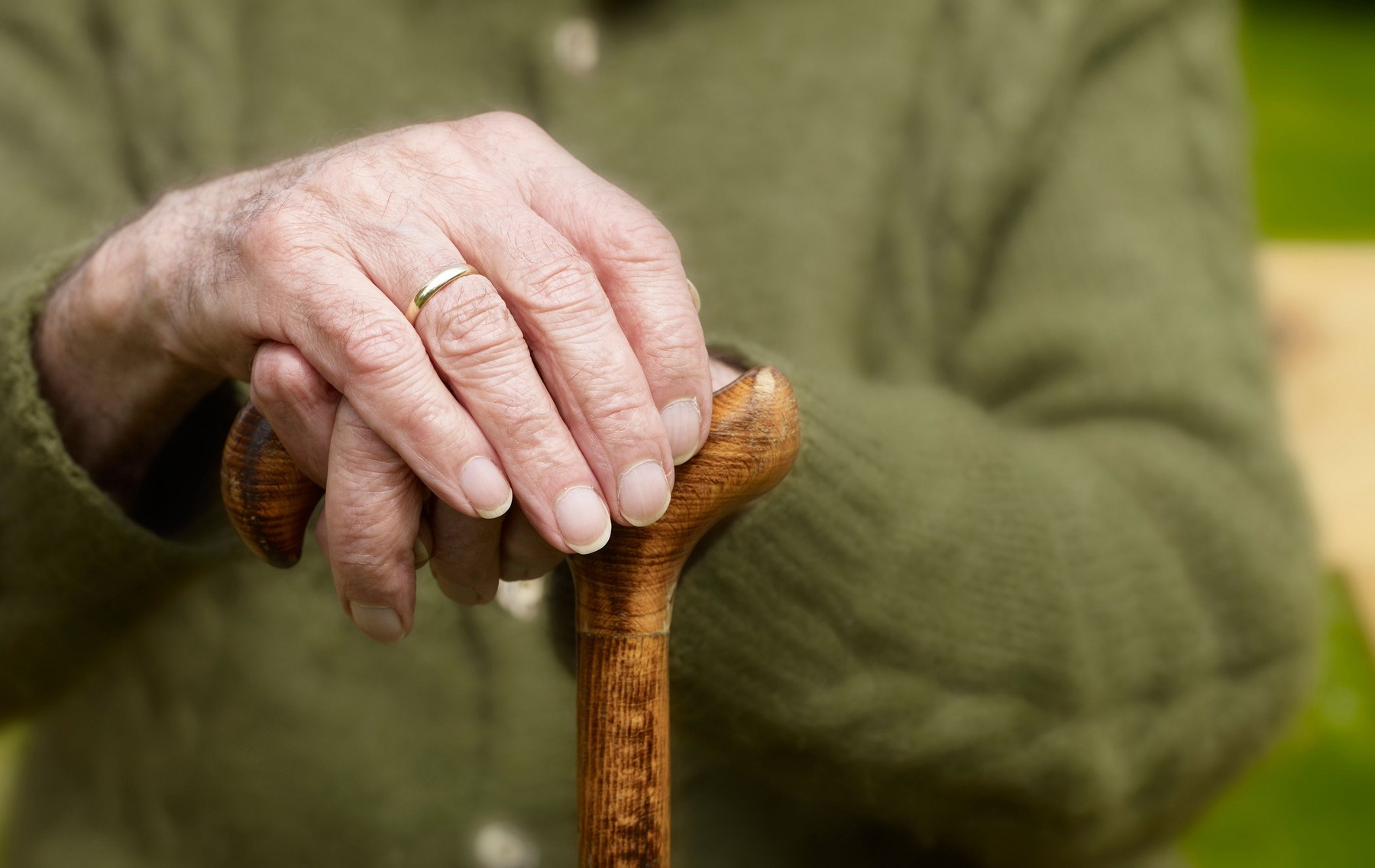 Starejša gospa, ki se z rokami drži oporne palice za hojo