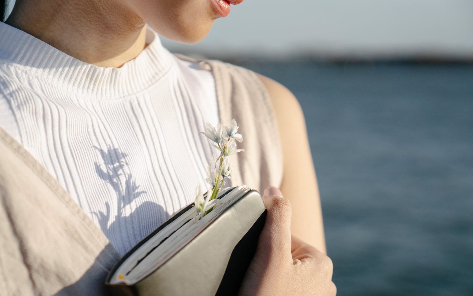 ženska ob morju z dnevnikom pexels