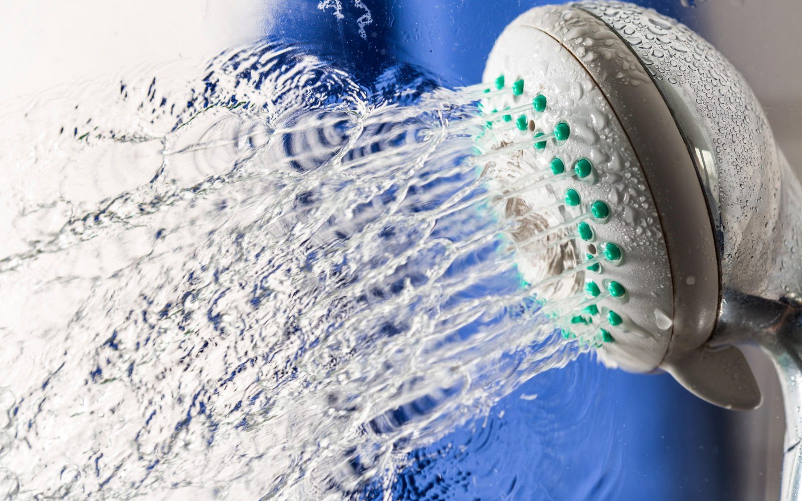 Fotografija prikazuje tuš glavo, iz katere teče voda, kar simbolizira osvežitev in higieno. Slika poudarja pomembnost vsakodnevnega tuširanja za osebno higieno in dobro počutje. Idealna je za članke o zdravju, osebni higieni, kopalniških izdelkih in življenjskem slogu.