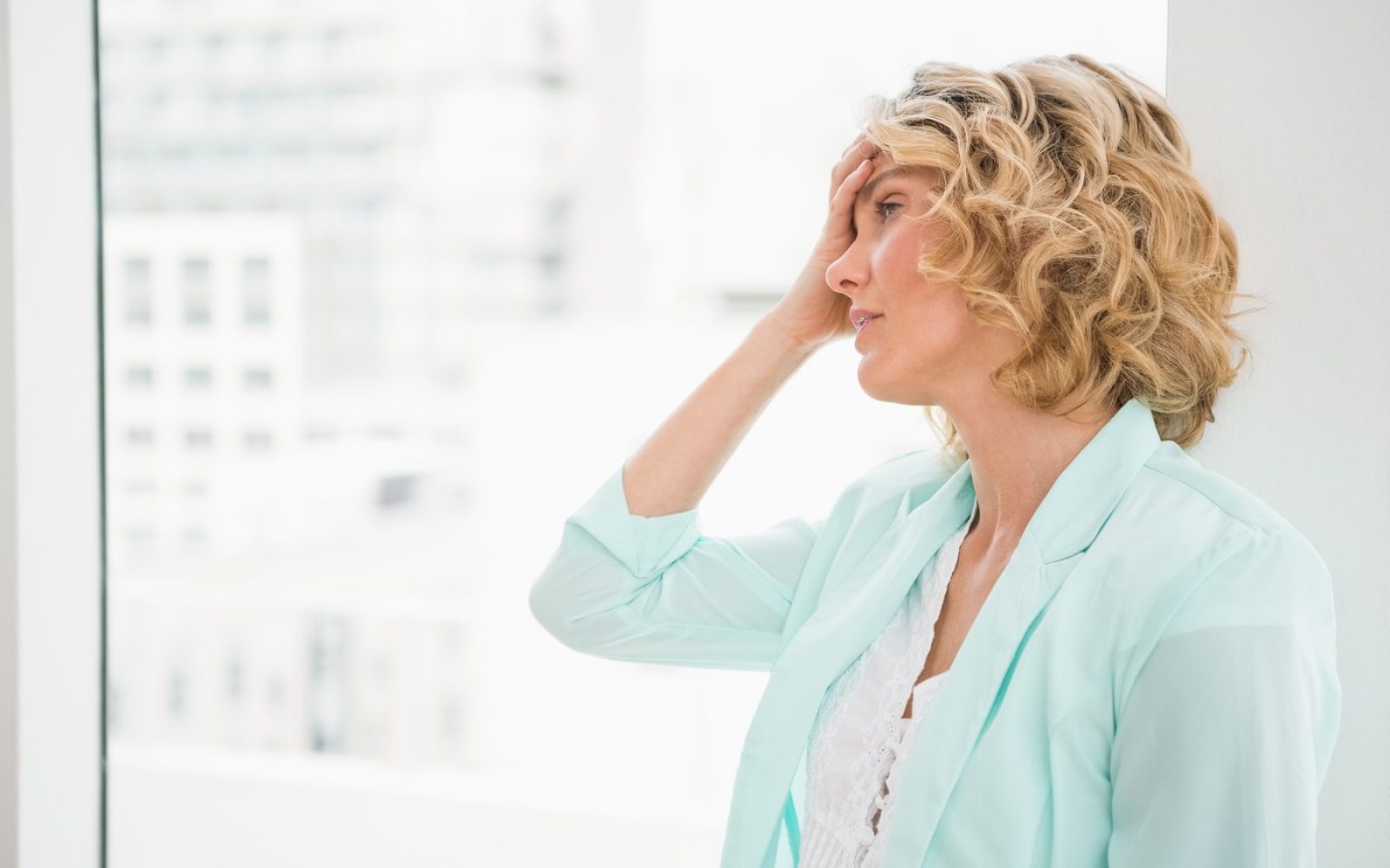 Lepa ženska se drži za glavo, ker jo pesti glavobol