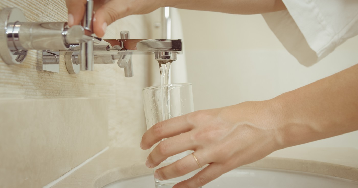 Ženska si toči v kozarec vodo iz pipe