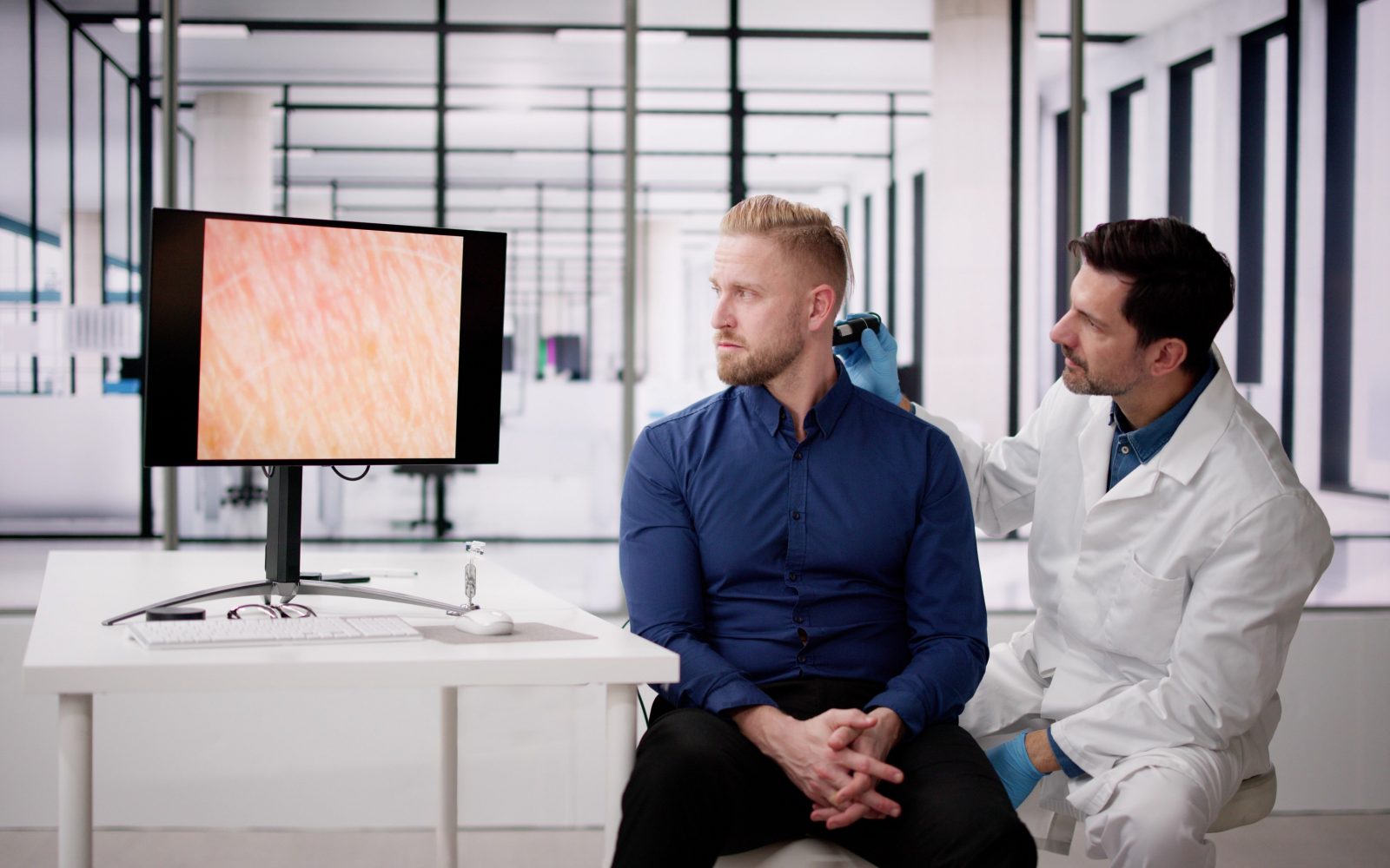 Dermatolog pregleduje moškemu znamenje