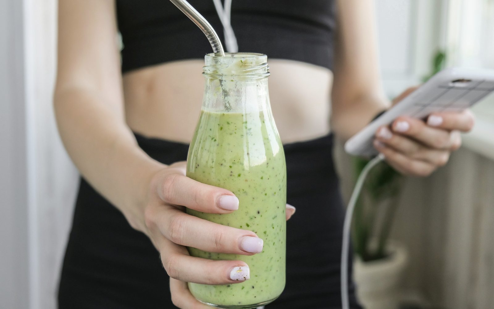 Ženska športnica v rokah drži smuti in telefon