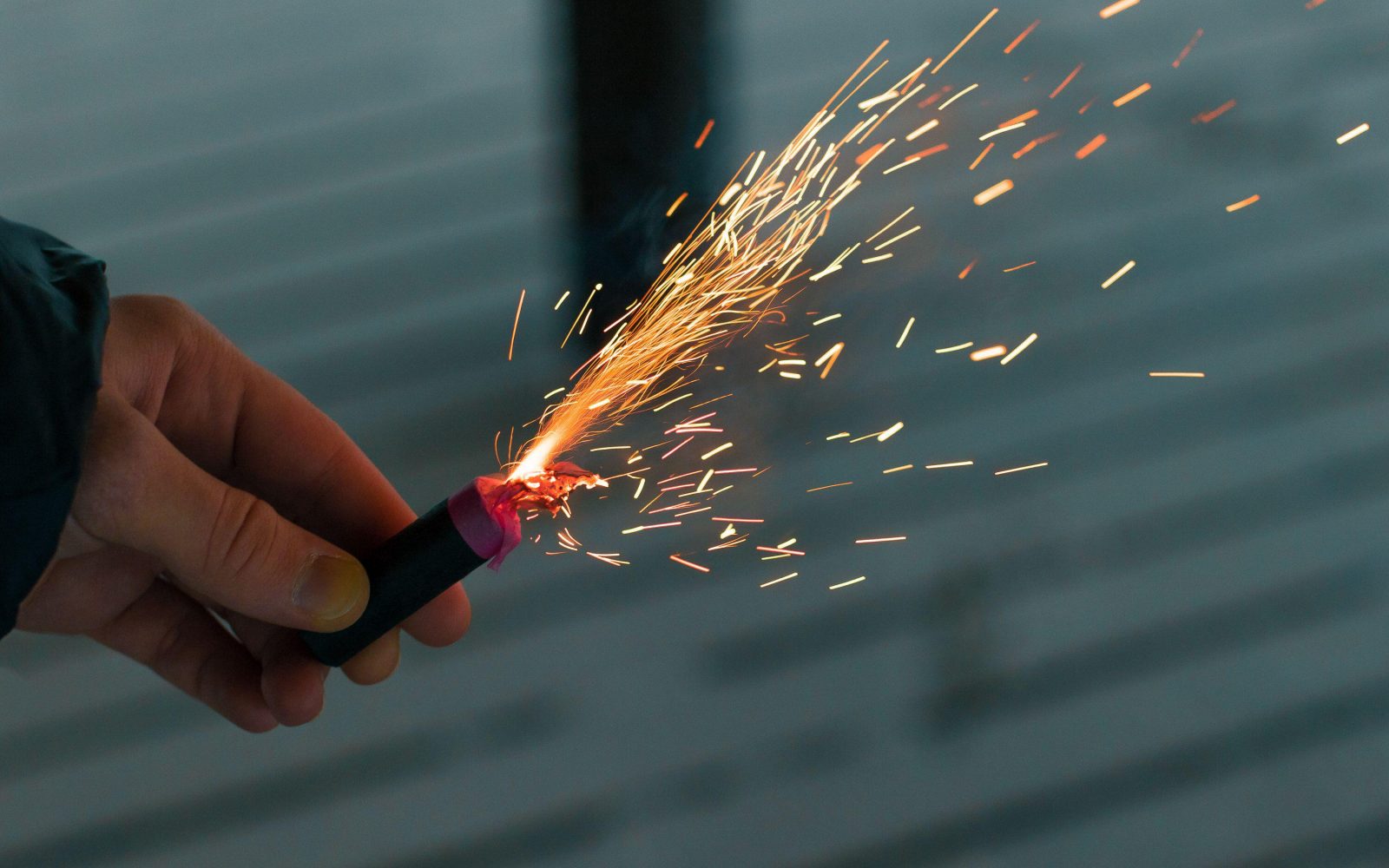 Nekdo v rokah drži prižgano petardo