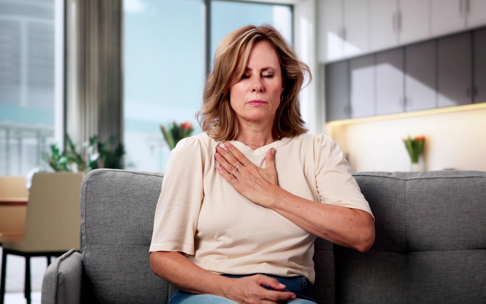 Ženska se drži za prsni koš, tišči oziroma boli jo v prsnem košu