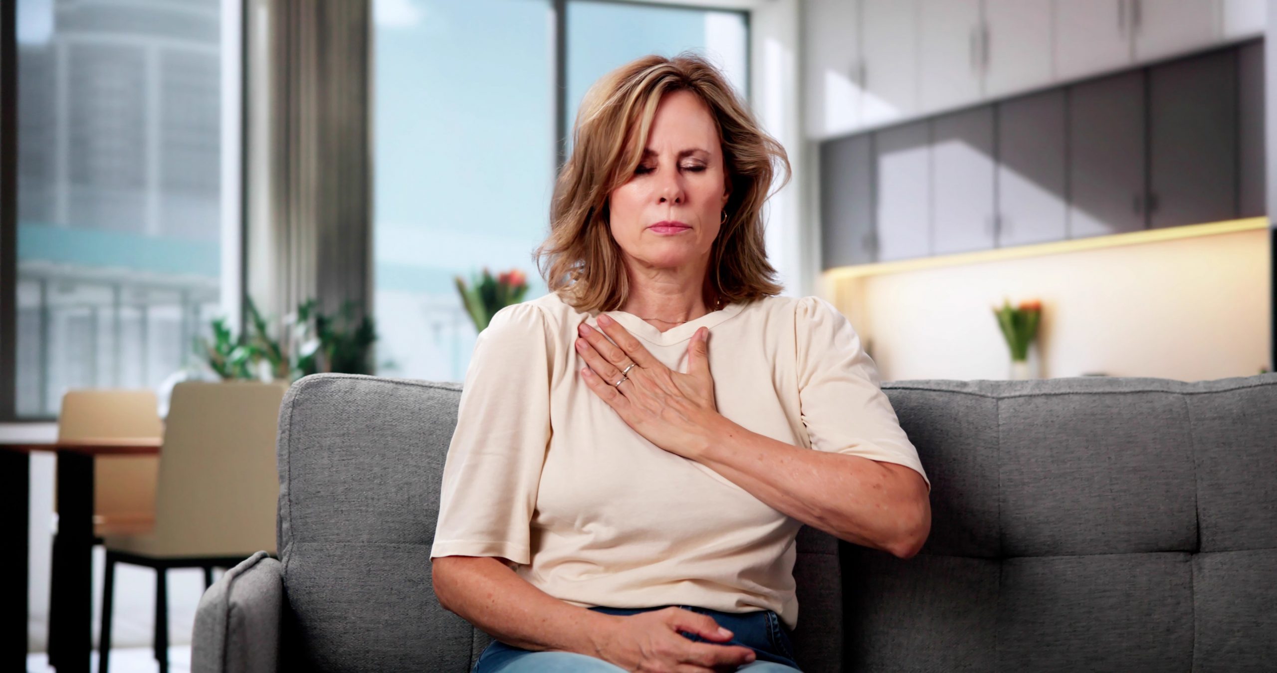 Ženska se drži za prsni koš, tišči oziroma boli jo v prsnem košu