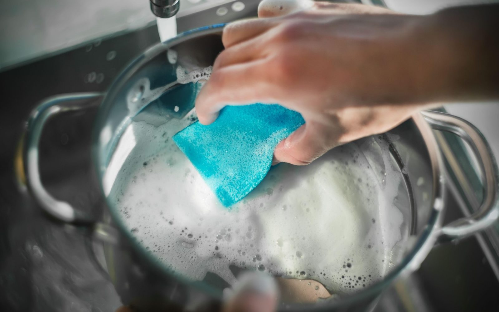 Oseba pomiva lonce z gobico, ki je polna bakterij in umazanije.