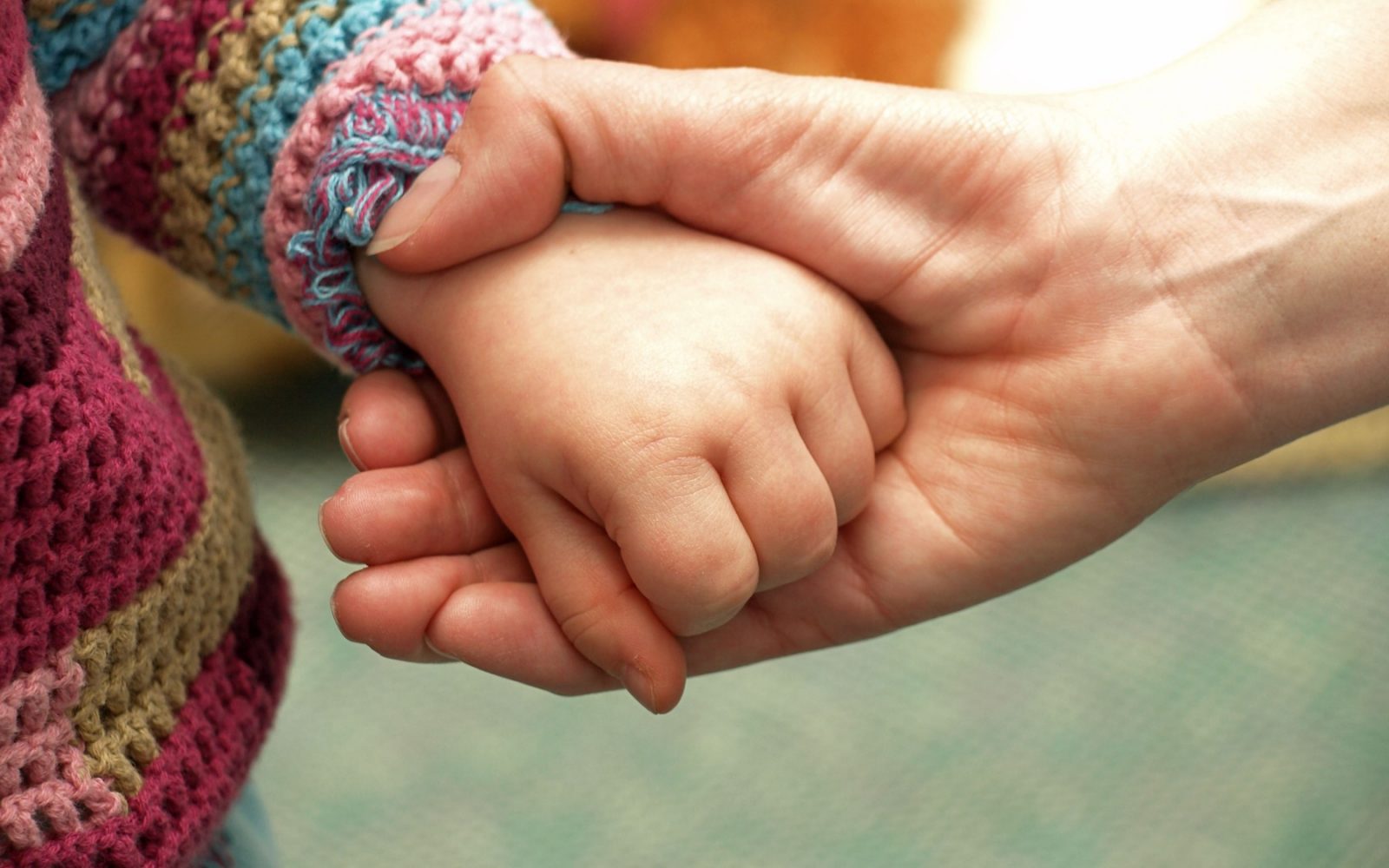 Odrasel drži otroško roko v svoji roki