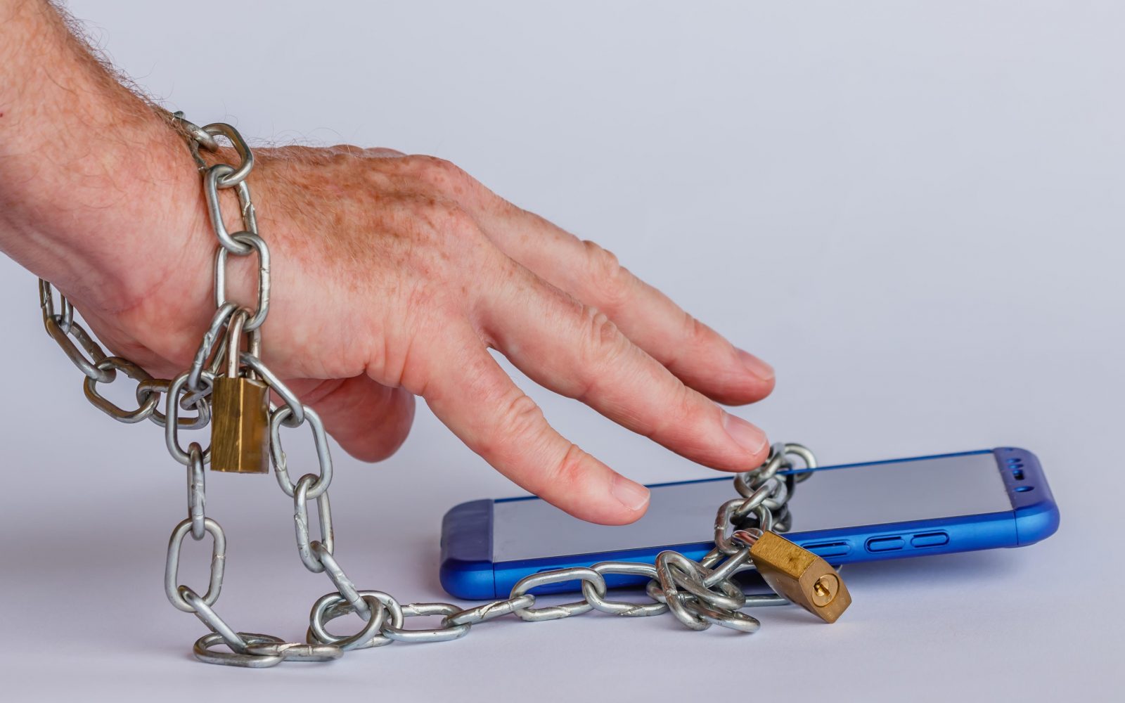 Simbolni prikaz odvisnosti od telefona: moški je z verigo priklenjen na telefon