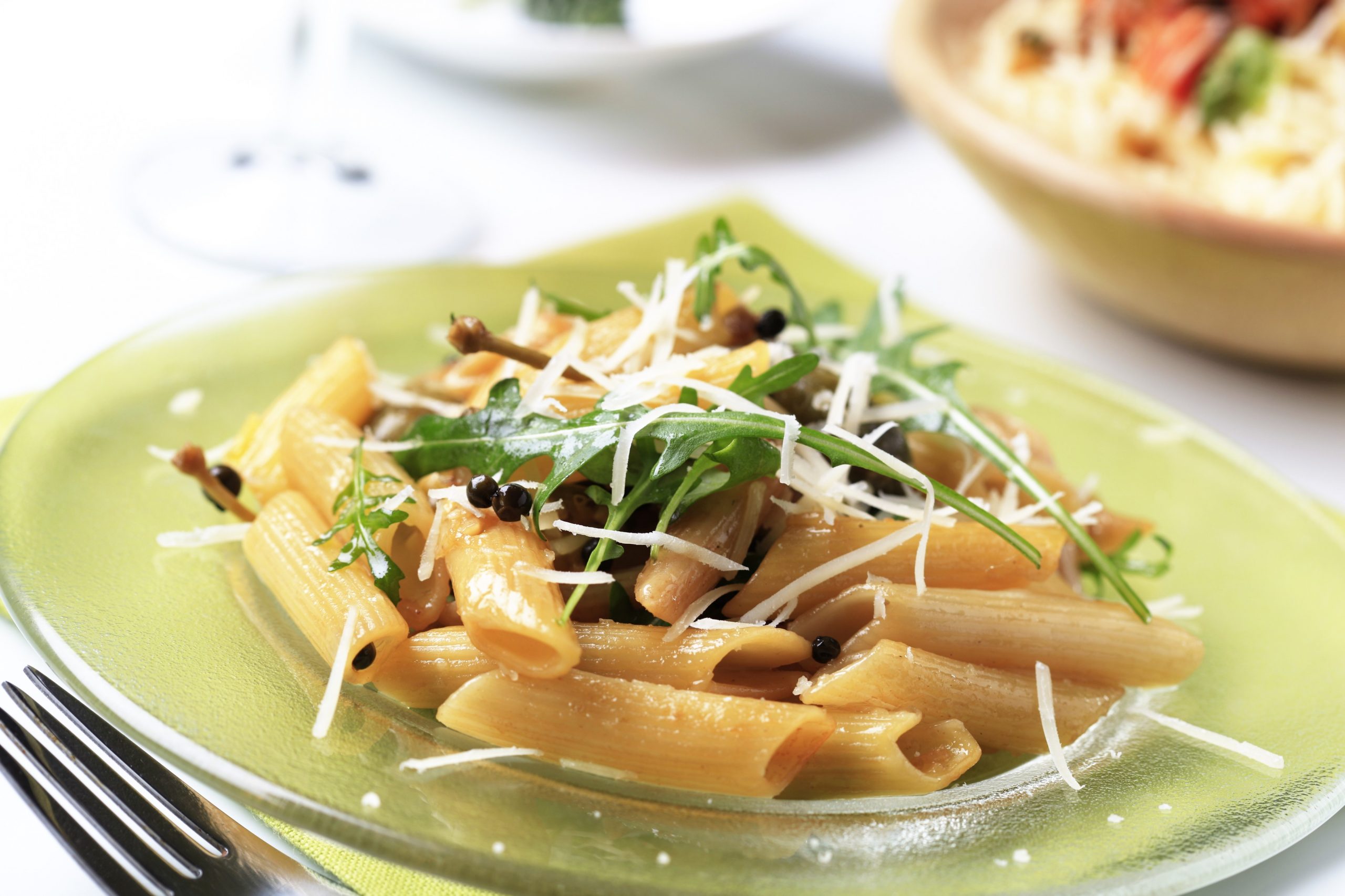 Makaroni na krožniku z rukolo in parmezanom