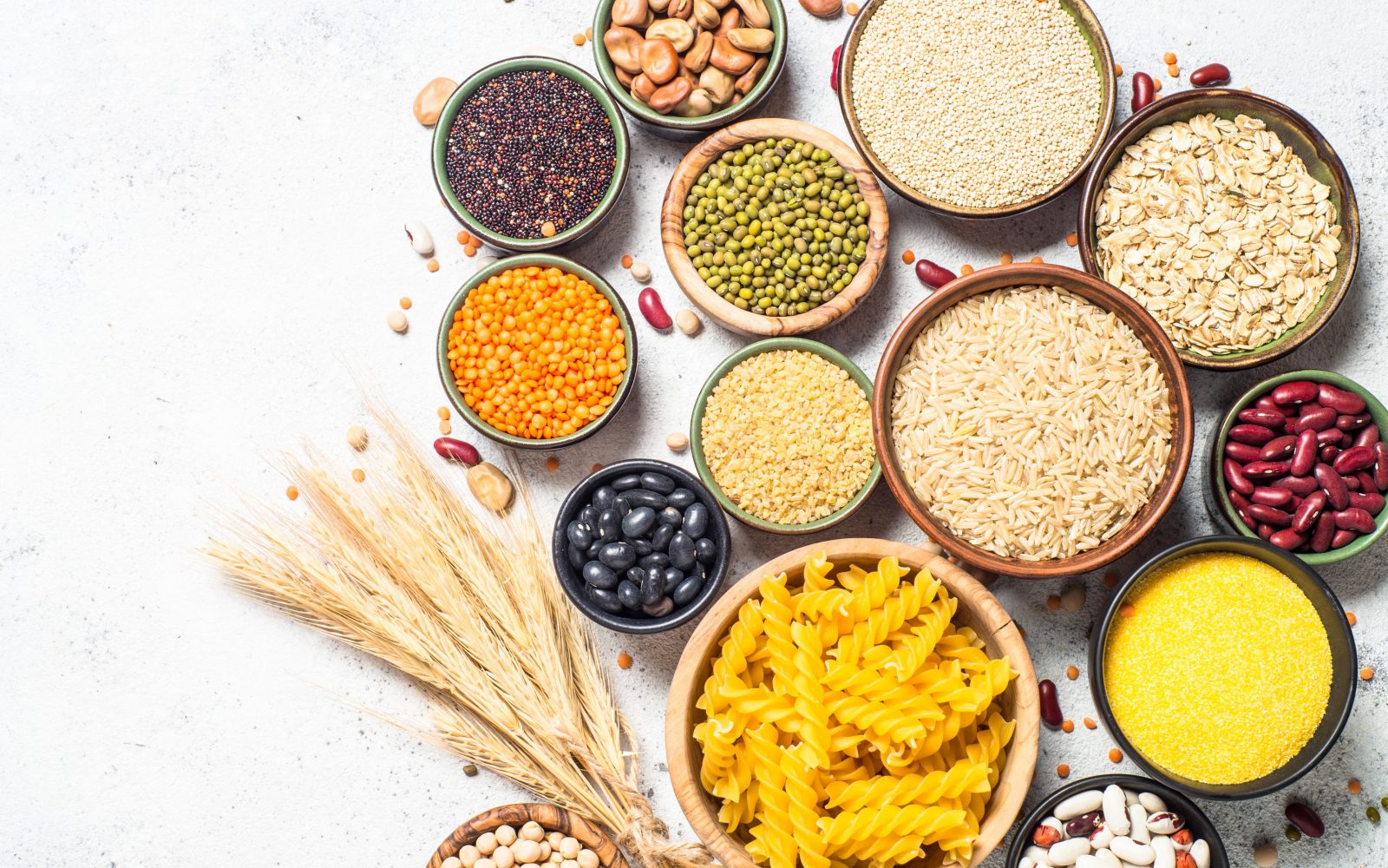 Na mizi so v posodicah različni prehranski izdelki, žita in stročnice, testenine in riž