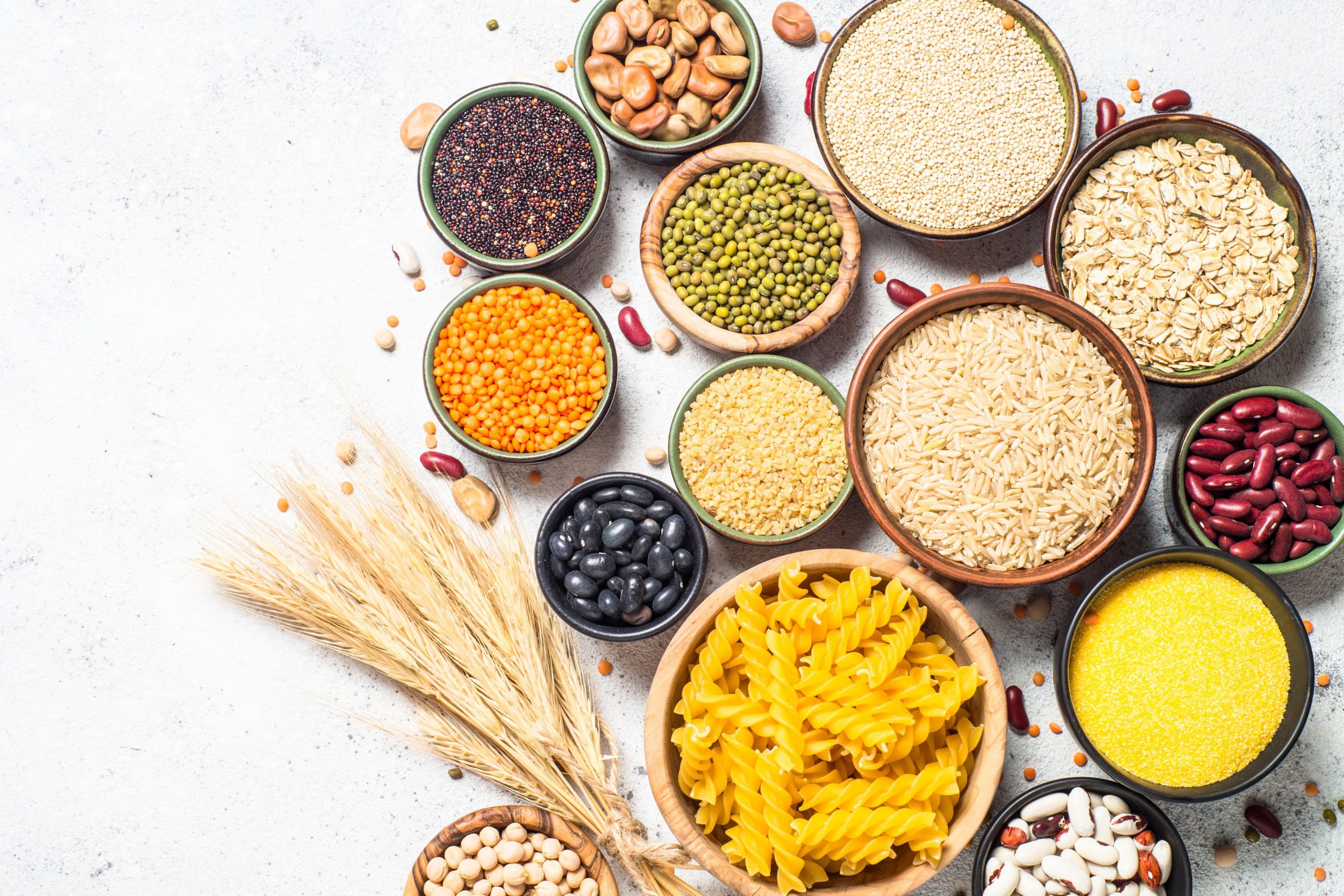 Na mizi so v posodicah različni prehranski izdelki, žita in stročnice, testenine in riž