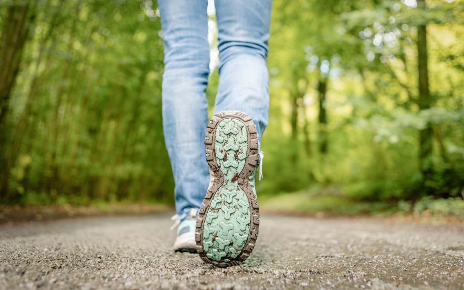 Hoja v gozdu, pogled od blizu na pohodne čevlje, ki hodijo po podeželski cesti, pogled od zadaj.