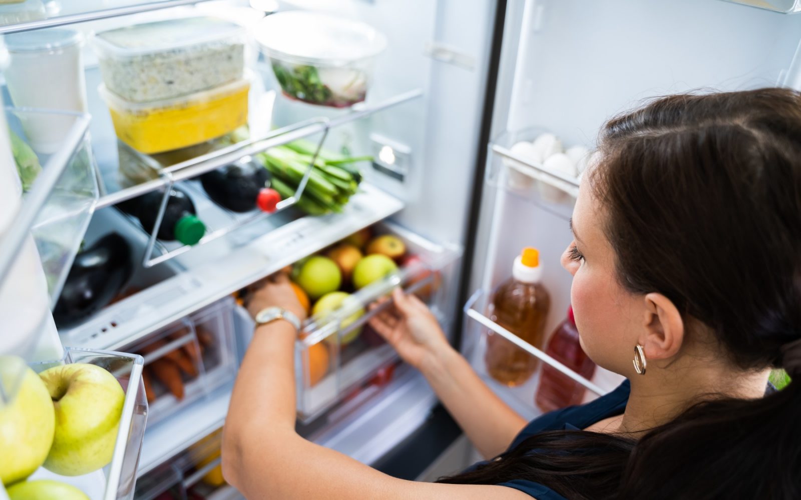 Ženska organizira živila v hladilniku, da podaljša njihovo svežino in zmanjša tveganje za okužbe s hrano.