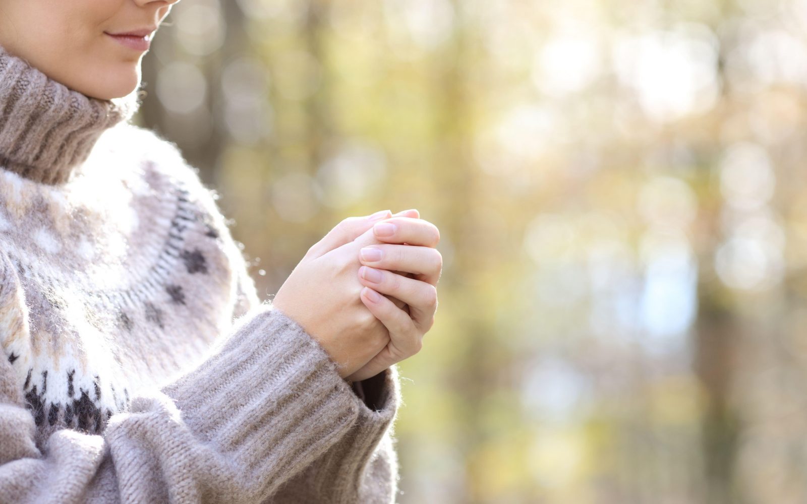 ženska si ogreva roke v mrzlem vremenu