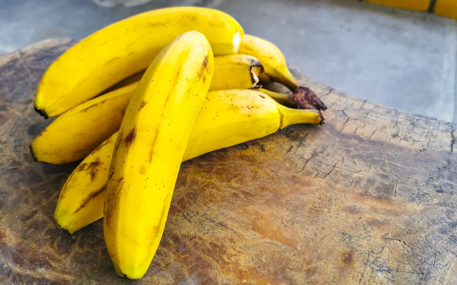 Zrele rumene banane s temnimi madeži na leseni deski – sveže tropsko sadje