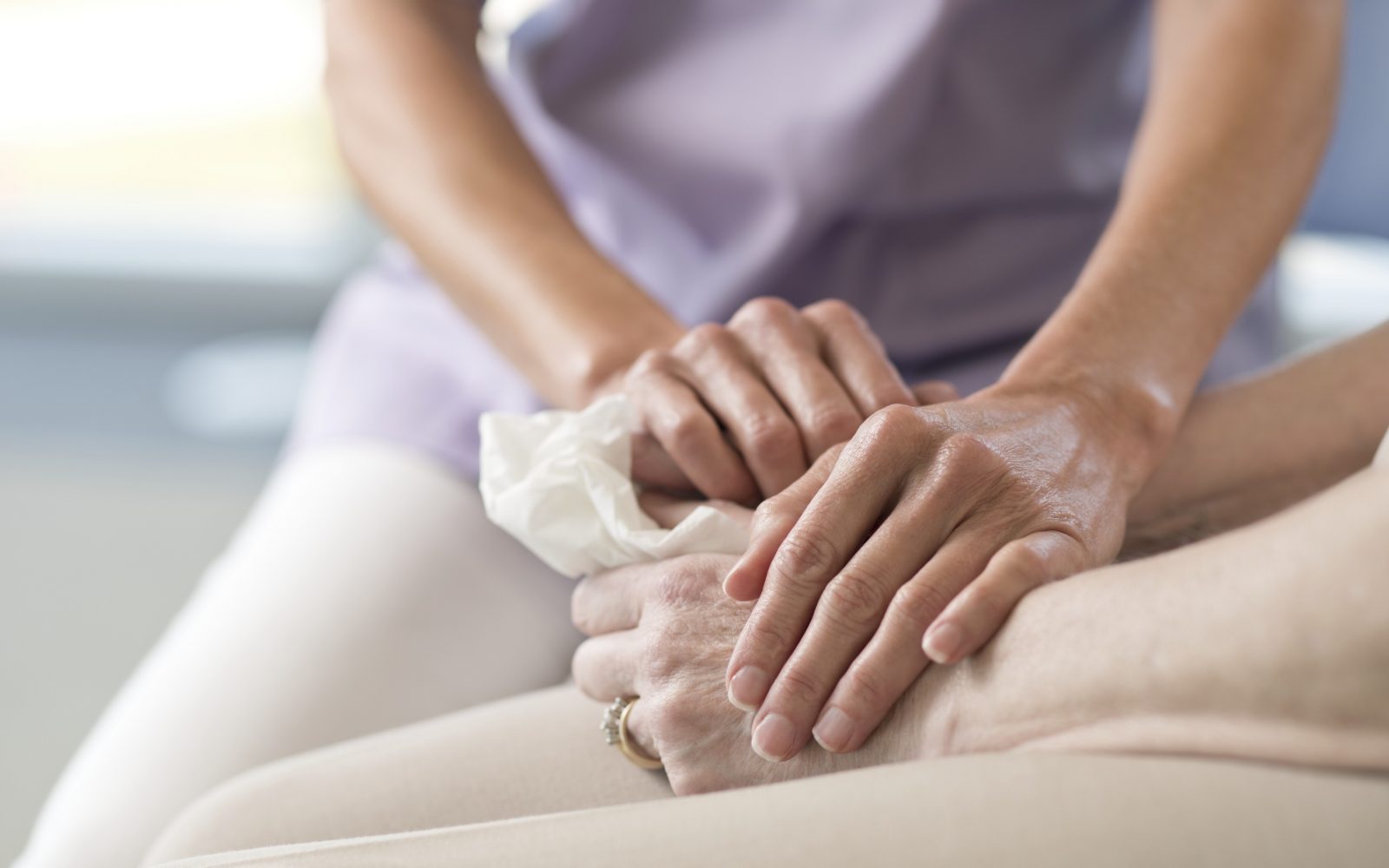 Ženska drži starejšo bolnico za roke, v znak čustvene podpore