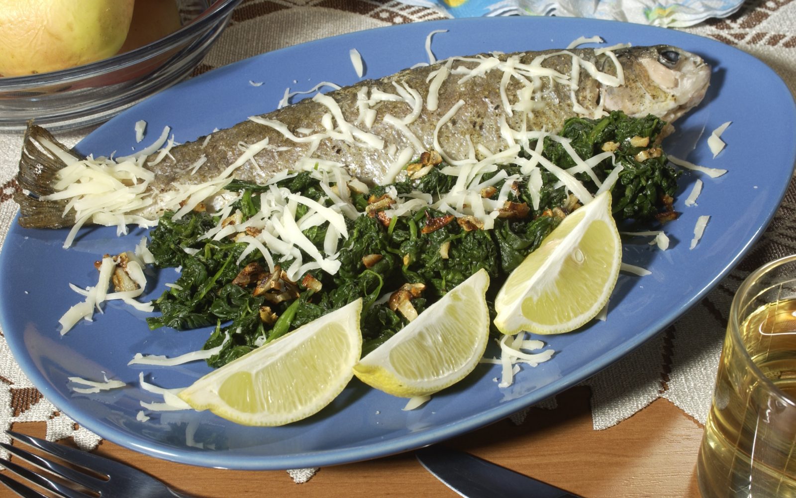 Na krožniku je postrv s hrenom, špinačo in limonami