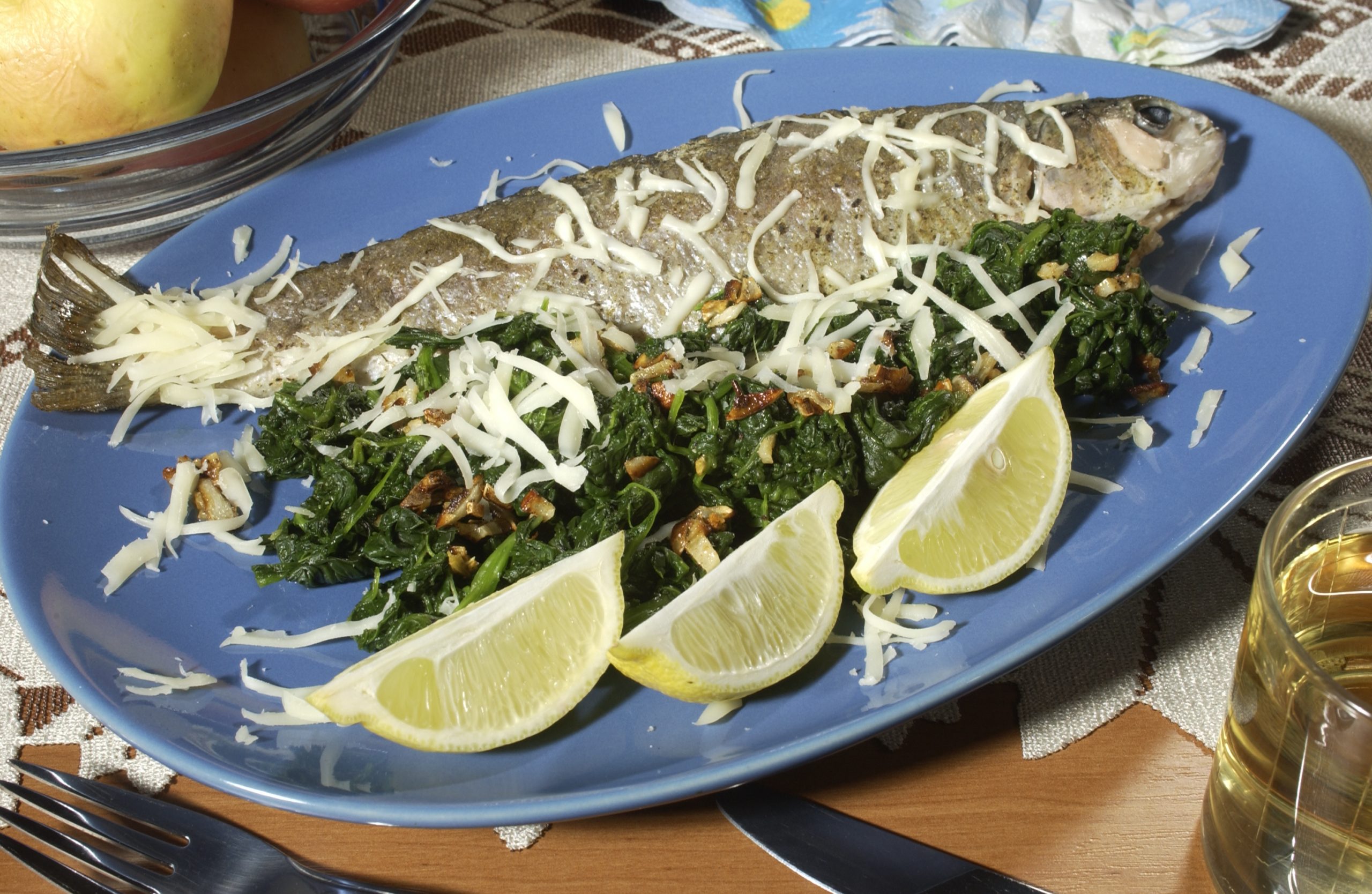 Na krožniku je postrv s hrenom, špinačo in limonami