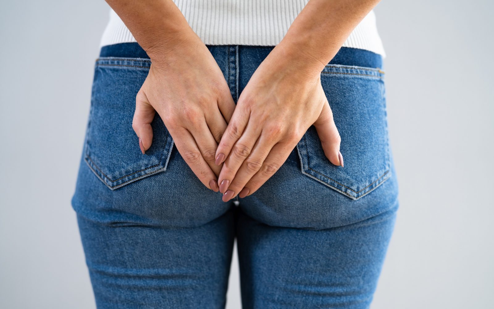 Ženska se drži za zadnjico, simbolni prikaz težav s hemoroidi