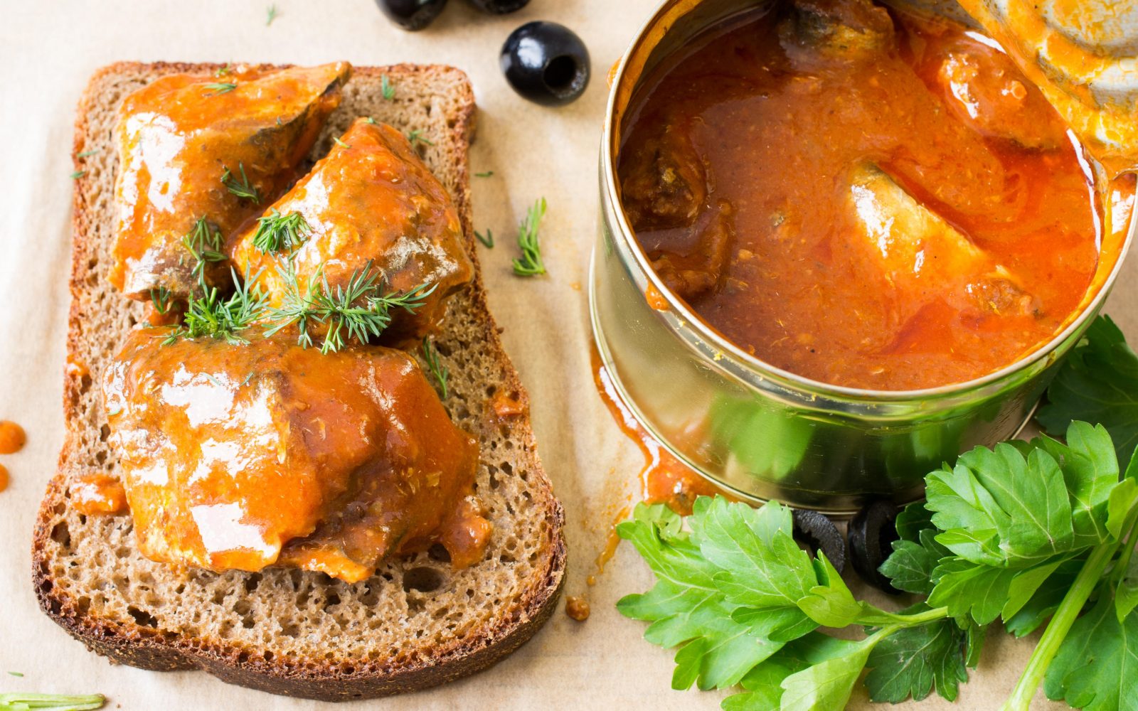 Na mizi je polnozrnat kruh s konzervirano ribo v paradižnikovi omaki