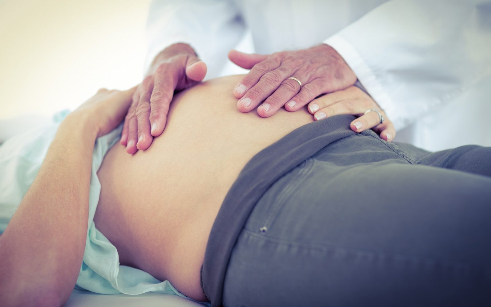 Fotografija nosečnice na zdravniškem pregledu, ki simbolizira pomen zdravstvene oskrbe v nosečnosti in preprečevanja materinske umrljivosti.