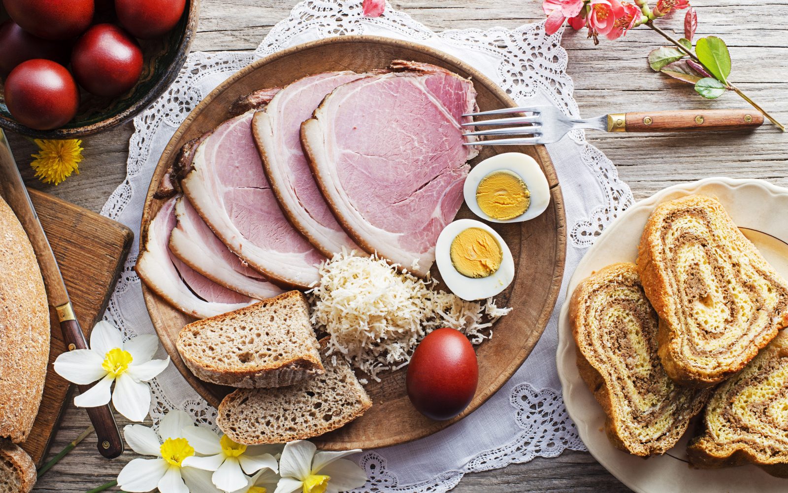 Praznična velikonočna miza s tradicionalno velikonočno hrano. Na krožniku so jajca, šunka, hren, kruh in potica.