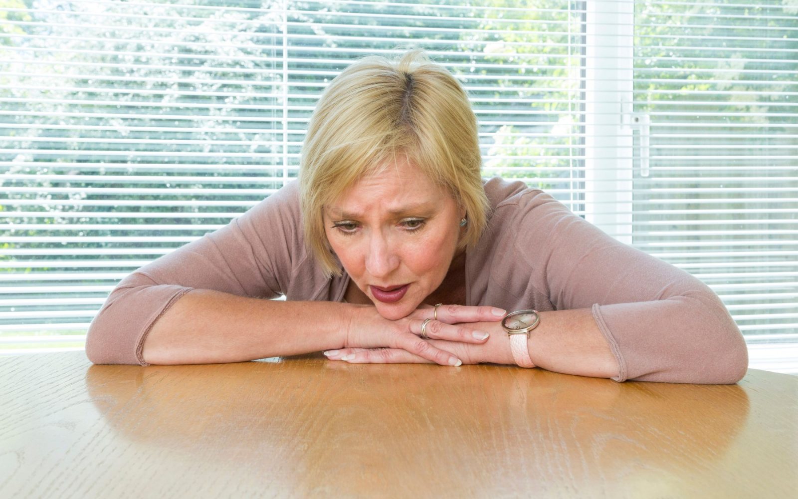 zaskrbljena in prestrašena ženska srednjih let za kuhinjsko mizo