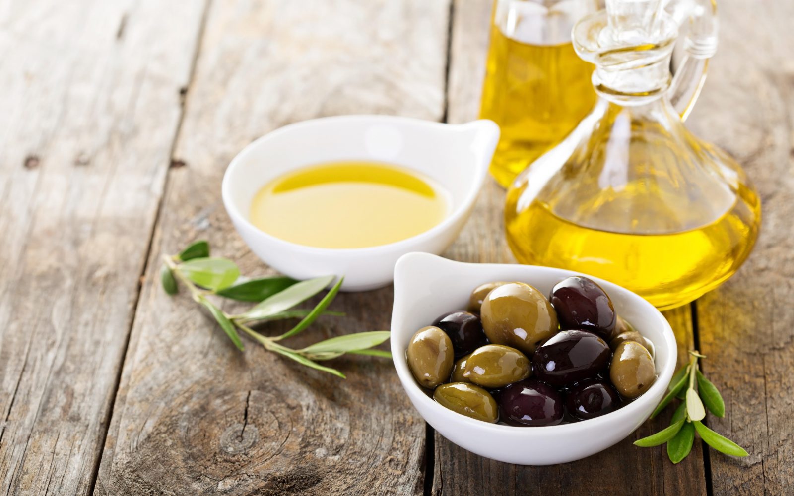 Na leseni mizi je posodica z olivami in olivnim olje