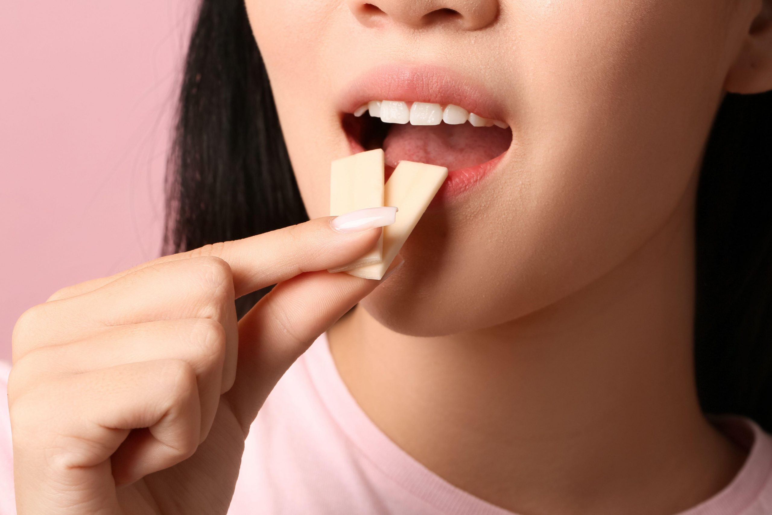 Ženska z lepimi zobmi daje v usta dva kosa žvečilnega gumija