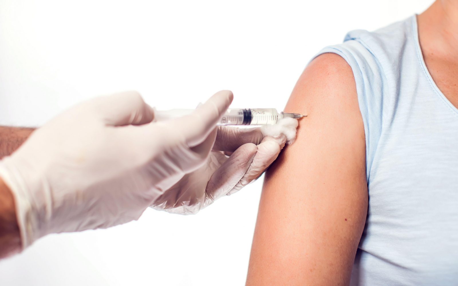 Zdravstveni delavec s sterilnimi rokavicami daje injekcijo v nadlaket odrasle osebe – imunoterapija proti alergiji.
