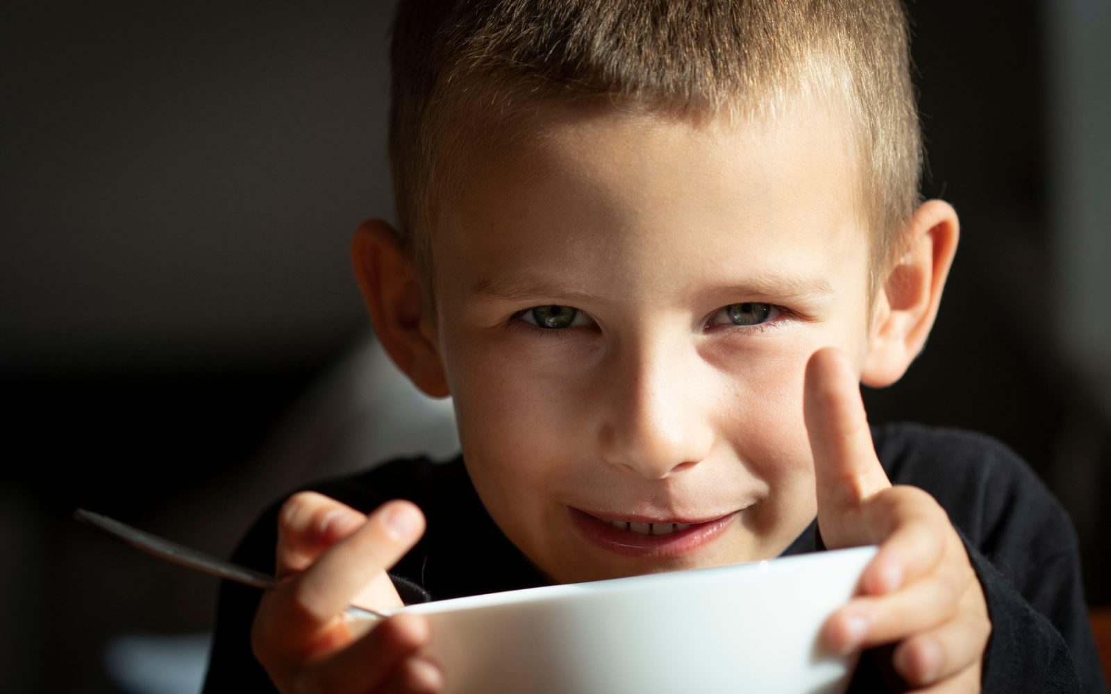 Otrok, ki z veseljem je juho iz skodelice – simbol zdravja in okrevanja.